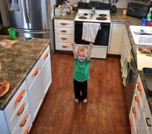 toddler grinning with both fists raised in triumph after he successfully balances a carrot on every single horizontal cabinet and drawer handle in the kitchen