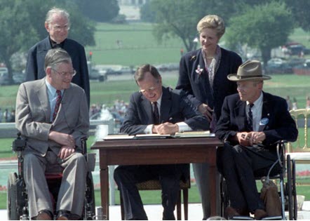 President George Bush, Sr. signing the ADA into law. He is surrounded by PWD