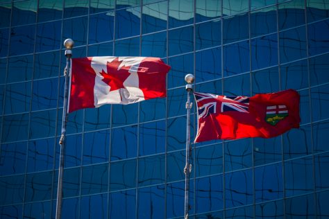Flags of Canada and Ontario against the glass front of a building, symbolizing Canadian accessibility laws.