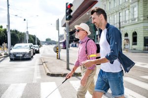 Diversity and inclusion example photo: Blind man with a cane crossing a street while in conversaion with his companion. They are not touching