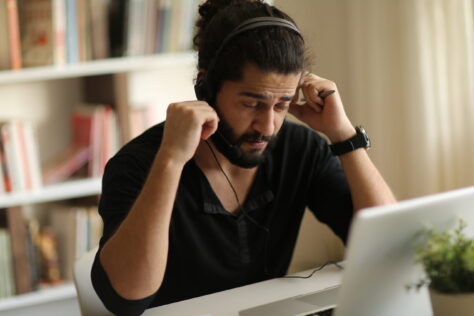 Frustrated man in headphones trying to read PDF document, dealing with poorly tagged PDFs.