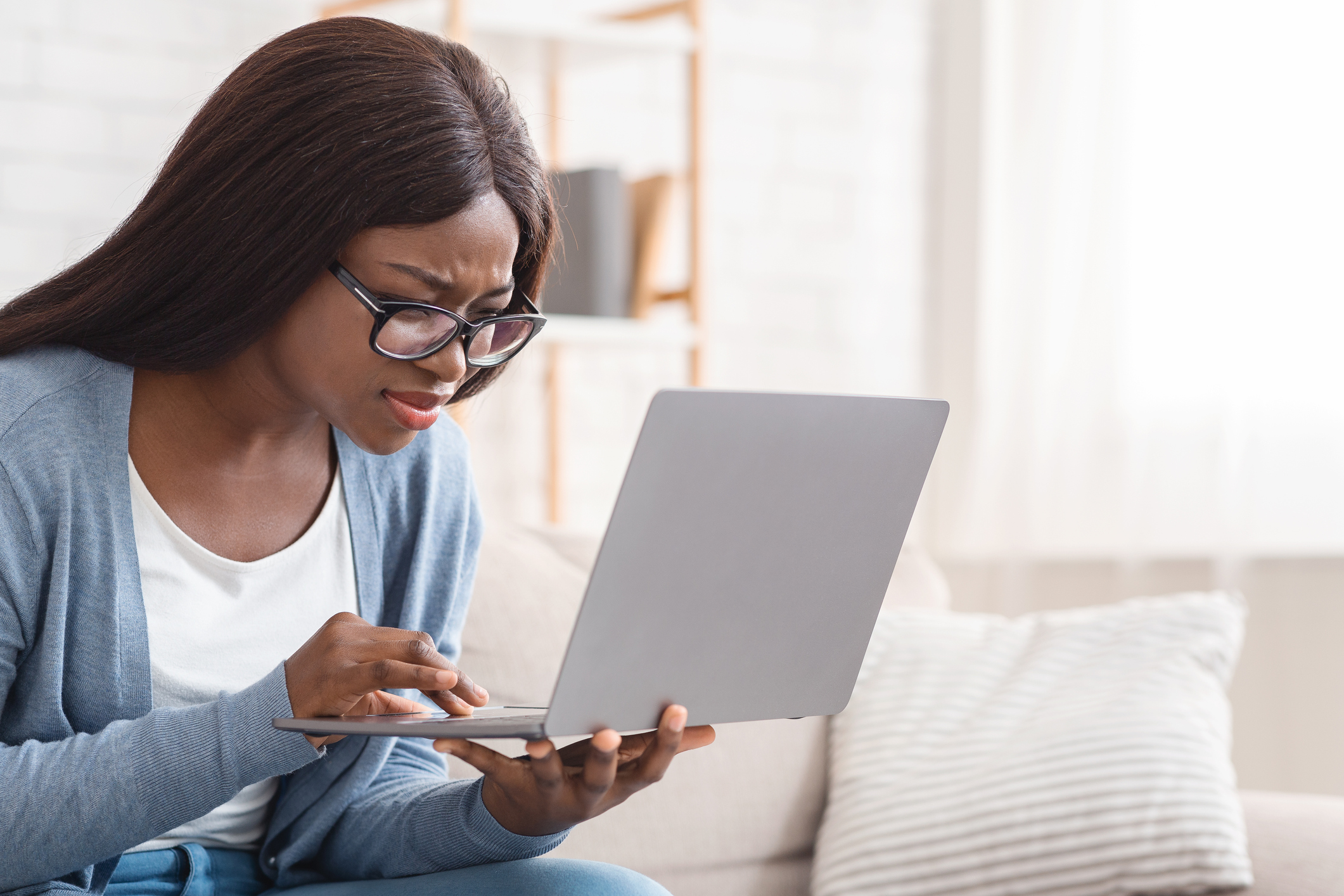 Woman in thick glasses squinting at a laptop