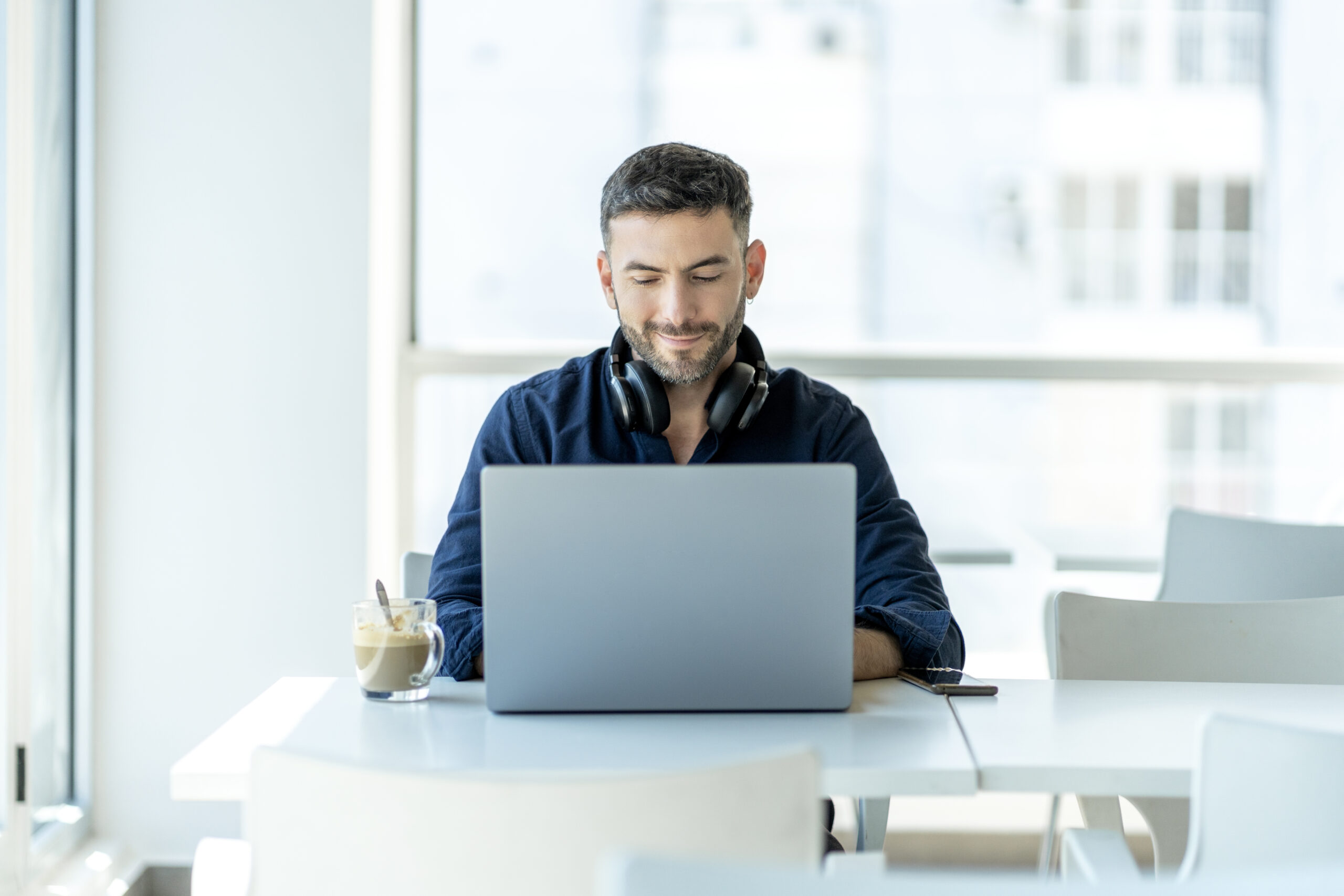 Man happily working on a laptop focusing on compliance as a competitive edge